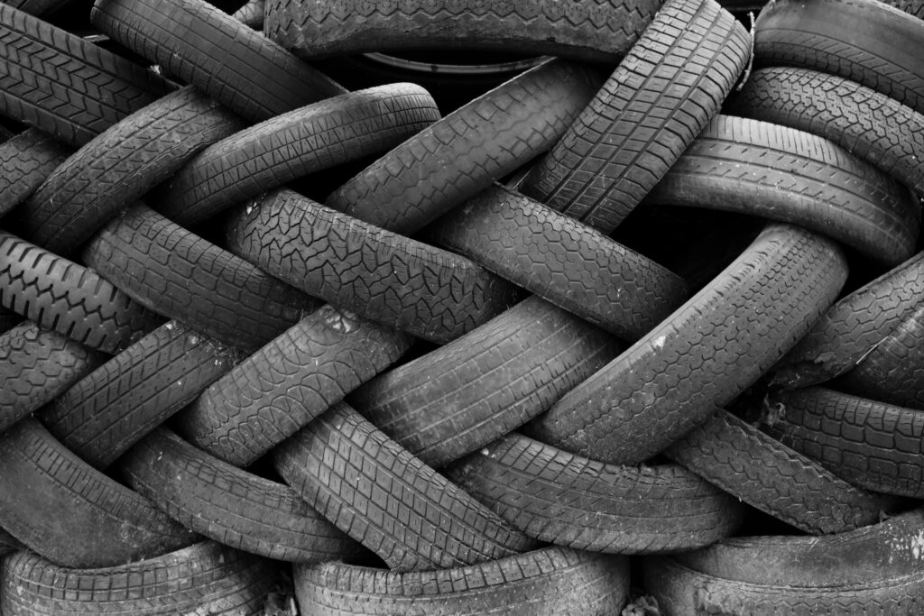 A black and white image showcasing a pile of old rubber tires intricately stacked, creating a textured pattern.